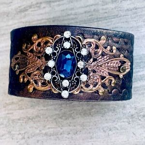 Upcycled belt cuff with blue stone and rhinestones on antique gold filigree.